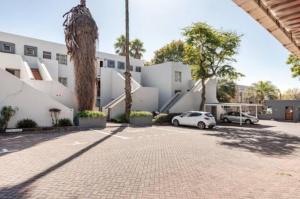 a parking lot with two cars parked in front of a building at Cozy loft with swimming pool in Johannesburg