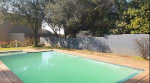 a large blue swimming pool in front of a fence at Cozy loft with swimming pool in Johannesburg
