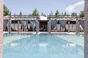 ein Swimmingpool in einem Resort mit einem Baldachin und einem Gebäude in der Unterkunft Charos Family Resort in Yusufkhona