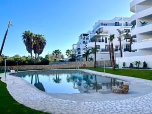 ein Schwimmbad vor einem großen Gebäude in der Unterkunft HOLY SEA Playa Granada Golf & Costa Tropical - Mar de Fabiola in Motril
