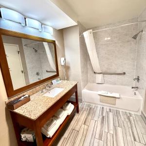 Un baño con bañera, lavabo y espejo. en Ramada by Wyndham Denver International Airport, en Denver 27 fotos más