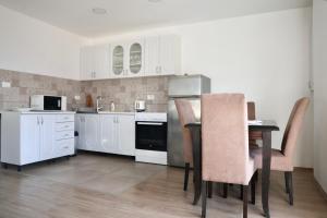 a kitchen with white cabinets and a table and chairs at Little Sunshine in Herceg-Novi