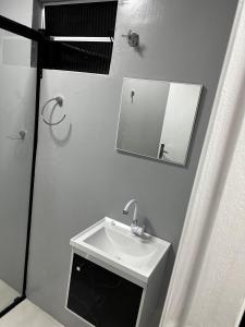 a white bathroom with a sink and a mirror at Loft Lux 9 Centro in Chapecó +1 photo
