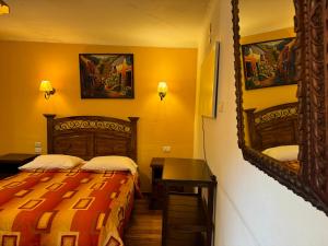 a bedroom with two beds and a desk and a mirror at Hostal Mallqui in Cusco