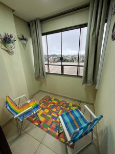 カネラにあるConfortável apartamento no centro de Canelaの窓付きの客室で、椅子2脚とラグ1枚が備わります。