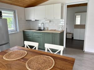 a kitchen with green cabinets and a wooden table at Przystań Ogrodowa Mikołajki in Mikołajki