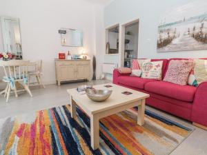 a living room with a red couch and a coffee table at Beachcomber in Marazion