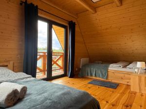 two beds in a room with a large window at Domy z sercem in Pilchy