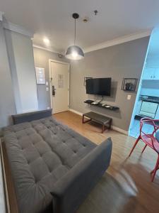 a large couch in a living room with a television at Hotel Aeroporto Congonhas com cozinha e sacada 1108 S in São Paulo
