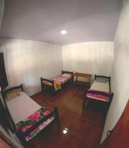 a room with three beds and a wooden floor at Hostel Lençóis em Santo Amaro MA in Santo Amaro +31 photos