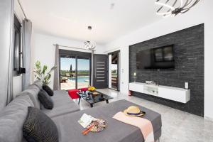 a living room with a gray couch and a tv at Villa Elysian in Afantou