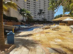 a swimming pool with tables and chairs and a building at Flat de 1 Qto Golden Dolphin Roberto Imóveis in Caldas Novas