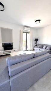 a living room with a large couch and a tv at Aroniadika rooms in Kýthira