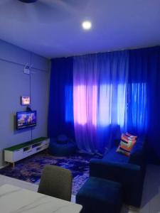 a room with blue curtains and a couch and a tv at Pemandangan tepi pantai rumah keluarga 6pax in Kuantan