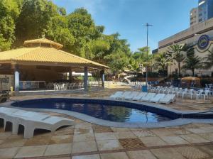 een zwembad met witte stoelen en een paviljoen bij flat 2 qtos Golden Dolphin Roberto Imoveis in Caldas Novas