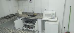 een kleine keuken met een spoelbak en een magnetron bij flat 2 qtos Golden Dolphin Roberto Imoveis in Caldas Novas