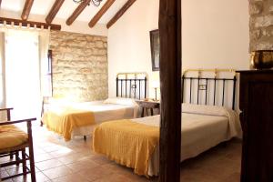 a bedroom with two beds and a stone wall at La Muralla in Sabiote