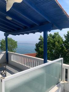 a blue pergola on a balcony overlooking the ocean at STUDIOs ARSINOI in Agia Paraskevi