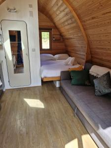 a bedroom with two beds and a couch in a room at Cosy Pod by The Moor & Fishing in Cheriton Bishop