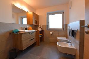 een badkamer met een wastafel, een toilet en een spiegel bij Lärchenheim Appartment in Castelrotto +7 foto's