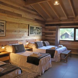 a bedroom with two beds in a log cabin at Estancia Chochoy Mallin Lodge ALL INCLUSIVE 