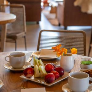 a table with a plate of fruit and two cups at Estancia Chochoy Mallin Lodge ALL INCLUSIVE 