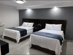 a bedroom with two beds with white sheets at Hotel Señorial in Puerto Peñasco