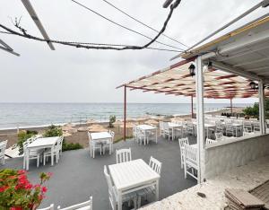 a patio with white tables and chairs and the ocean at The Garden Tiny Homes in Ayvacık