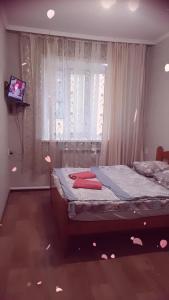 Un dormitorio con una cama con ventana y un televisor. en Гостевой Дом, en Karagandá