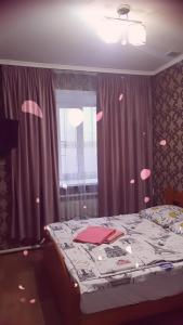 Un dormitorio con una cama y una ventana con corazones rosados. en Гостевой Дом, en Karagandá