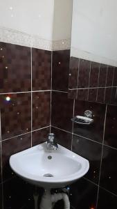 Baño con lavabo blanco y azulejos marrones en Гостевой Дом, en Karagandá