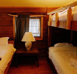 a bedroom with two bunk beds and a table with a lamp at Rustic Beaverfoot Lodge Room N8 in Parson