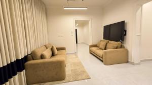 a living room with two chairs and a flat screen tv at شقق سكنية مفروشة فاخرة - مكة الشرائع in Ash Sharāʼi‘