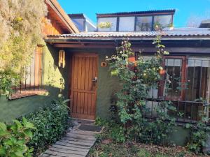 Una casa verde con una puerta de madera y enredaderas. en Cabaña El Camino, en San Martín de los Andes