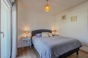 ein Schlafzimmer mit einem Bett und zwei Lampen an Tischen in der Unterkunft Appartement T2 idéal 2 personnes-150 m de la plage in Biscarrosse
