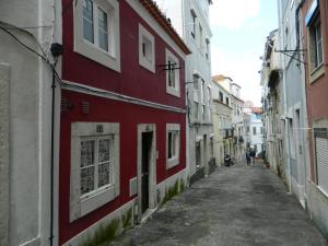 un vicolo con un edificio rosso e una persona che cammina lungo la strada di Feel Alfama Apartment a Lisbona