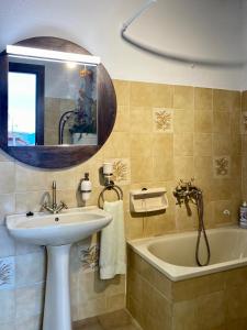 a bathroom with a sink and a tub and a mirror at Lakis' Wellhouse in Ano Poroia +11 photos