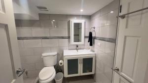 a bathroom with a toilet and a sink and a mirror at 1-bedroom One Woodbrook Place Apartment! in Port-of-Spain