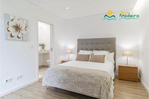 a white bedroom with a large bed and two lamps at OurMadeira - Calheta Heights, modern in Calheta +16 photos