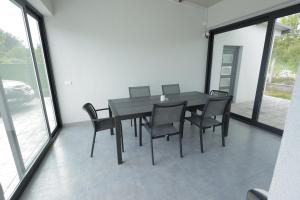 a black dining room table and chairs in a room with windows at Danka Pool House in Usije