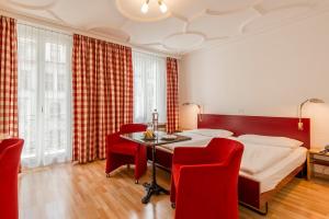 1 dormitorio con 1 cama, mesa y sillas en Hotel Alpina Luzern, en Lucerna