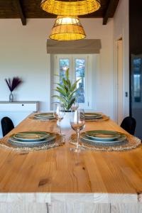 a wooden table with plates and wine glasses on it at Amalia Casa Lefkada in Pigadhisánoi