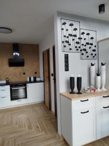a kitchen with white cabinets and a wooden floor at Domek letniskowy - Leśna chmurka - sauna, bania in Cewice