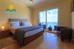 a bedroom with a bed and a chair and a window at OurMadeira - Casa da Belita, sea-view in Calheta +17 photos