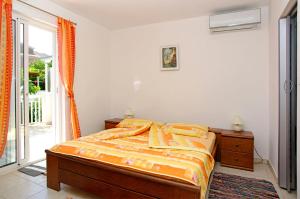 a bedroom with a bed with orange sheets and a window at Foissner Apartments in Zavalatica