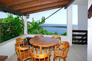 a wooden table and chairs on a porch with a view of the water at Foissner Apartments in Zavalatica