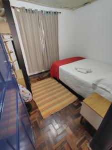 a small bedroom with a bed and a red blanket at Quarto Britney in Ouro Preto