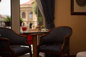 einen Tisch mit einem Teller Essen und zwei Stühlen in der Unterkunft Massimo Plaza Hotel in Palermo