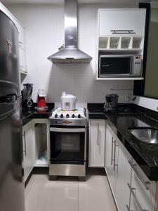 uma pequena cozinha com fogão e micro-ondas em GOLDEN LAKE, lugar para relaxar em Arraial do Cabo