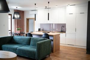 ein Wohnzimmer mit einer grünen Couch und einer Küche in der Unterkunft Willa Matejki - Apartament 7 in Przemyśl